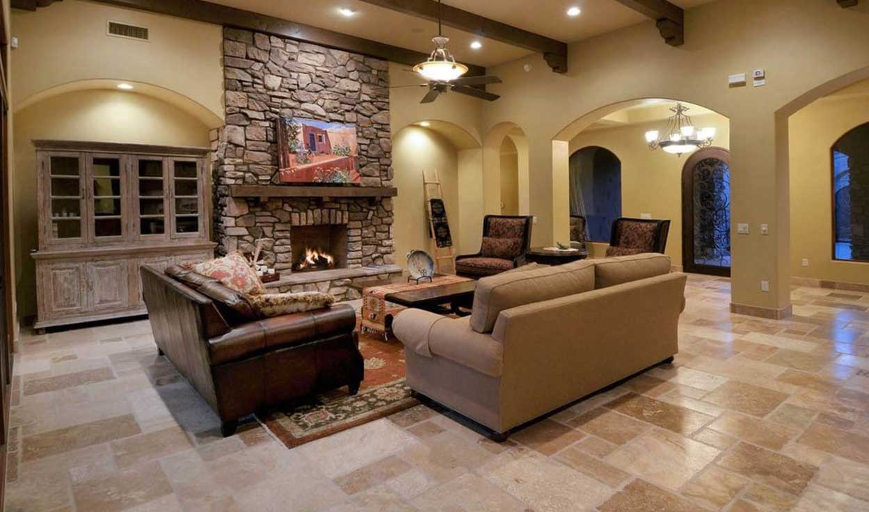 The living room of a Canyon Pass luxury home with tiled floors and a stone fireplace