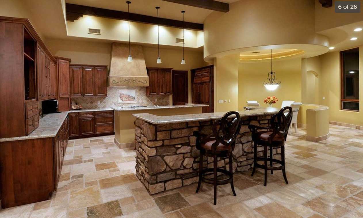 A gorgeous kitchen built by our Tucson custom home builders with a stone kitchen island, granite countertops, and dark wood cabinets