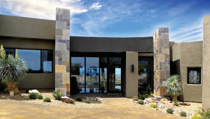 The entrance to a home in La Reserve build by our custom home builders, featuring large glass windows and stone tiles