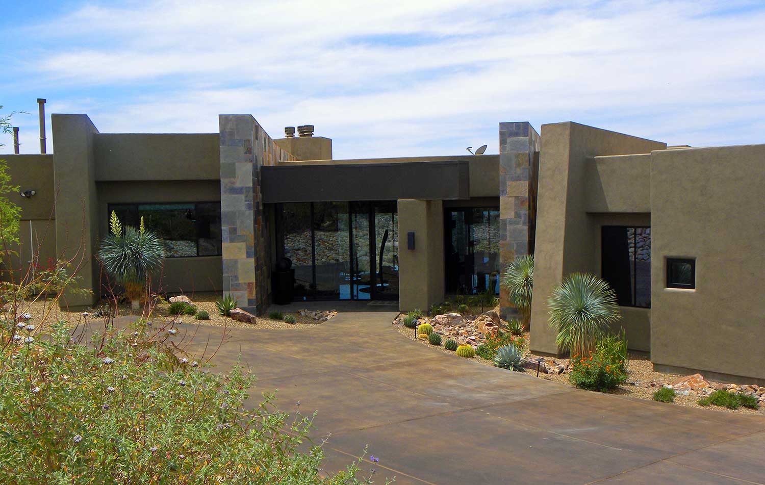 The driveway of a La Reserve luxury house with a wide living area with glass walls and windows