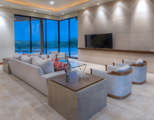 A sitting room in a custom home with tall glass windows looking out over the backyard