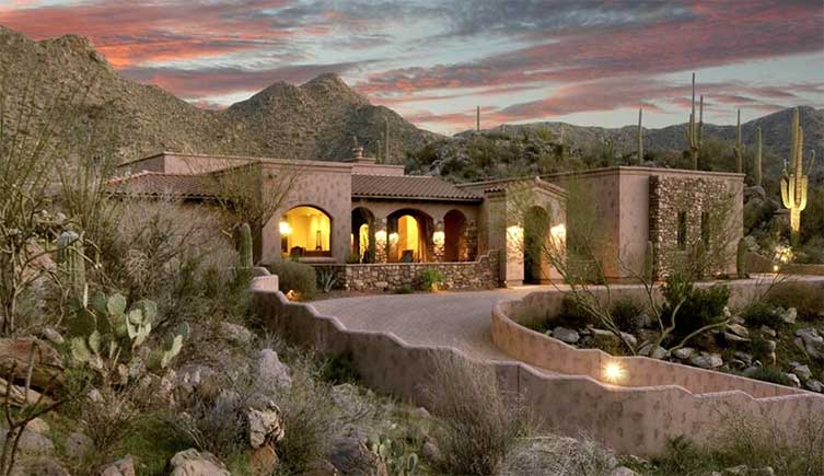 A luxury home with a desert sunset in the background